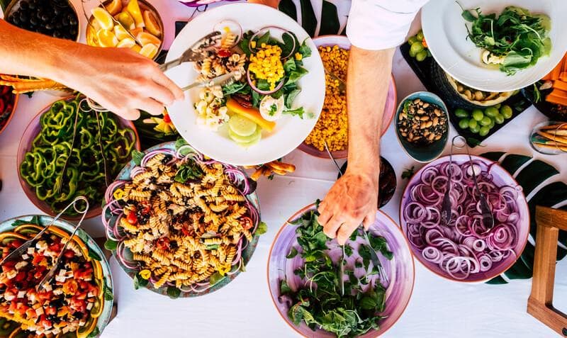 People together during party event celebration taking mixed healthy food from a table - fresh chef meal ingredients on a table- concept of catering and restaurant