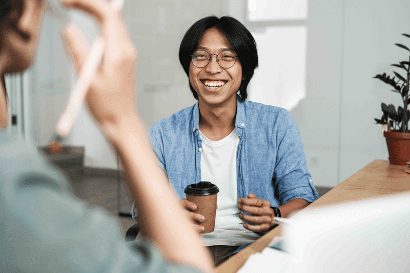 Image of multinational joyful colleagues discussing project and laughing